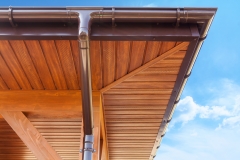 Brown copper gutter under a cloudy blue sky